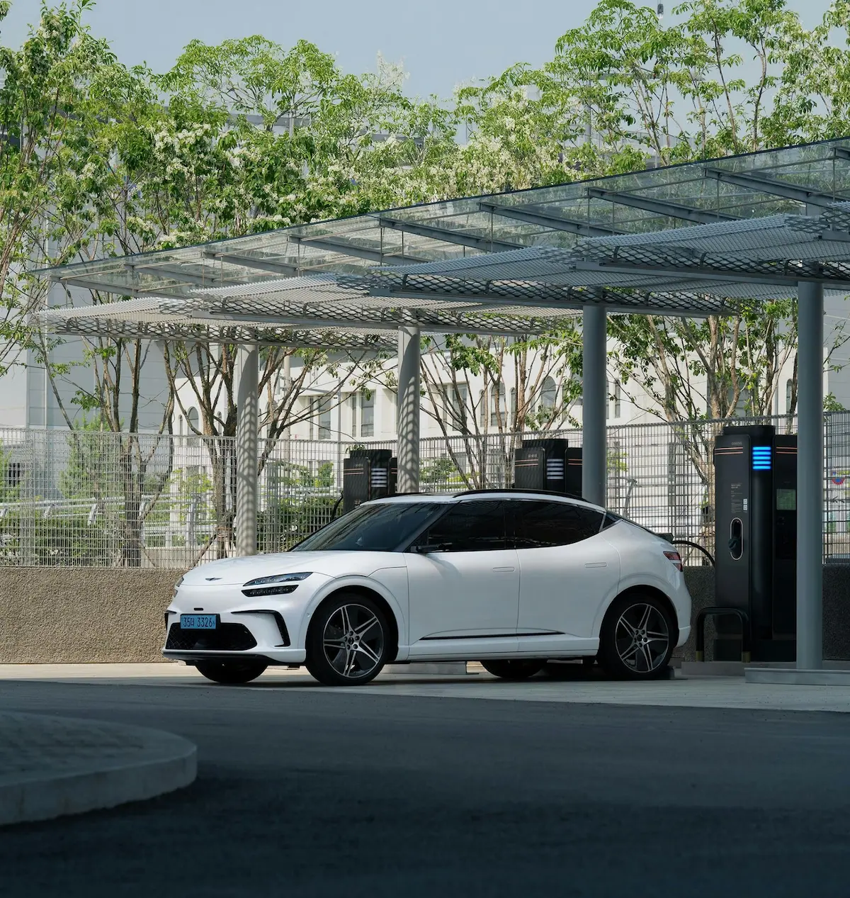 Borne de recharge électrique IRVE moderne avec véhicule blanc stationné sous une structure solaire design.